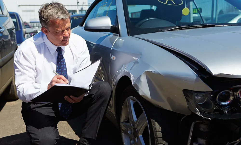 Professional assessing vehicle damage for an auto insurance claim