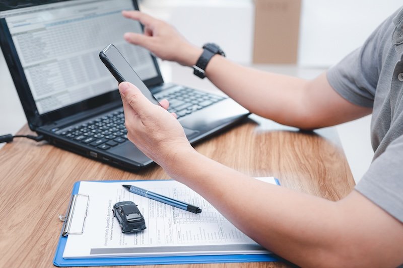 Service staff use smartphone Check details about car repairs compared to the data in laptop to estimate the cost of car repairs in office car service center collision repair timeline