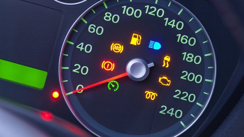 A closeup on the dashboard of a modern car with many warning lights.