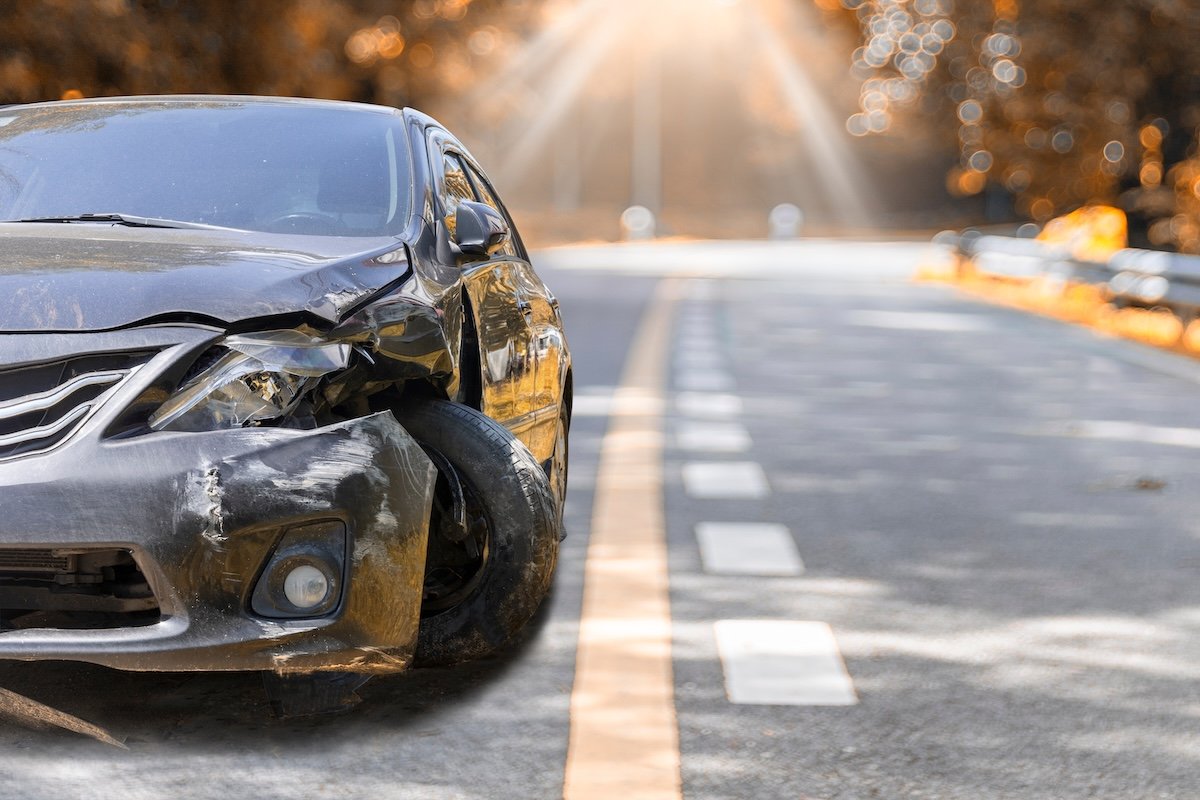 Artumn road. Front of black color car big damaged and broken by accident on road parking can not drive any more. With copy space for text or design