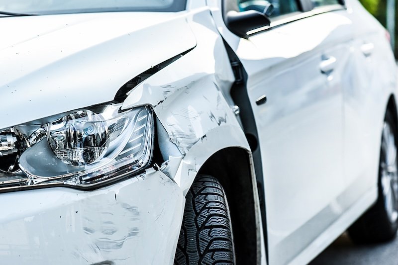 Car crash or accident. Front fender and light damage and scratchs on bumper. Broken vehicle detail or close up.