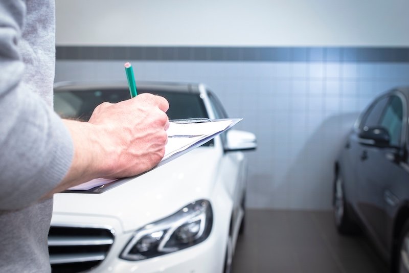 car service, repair, maintenance concept -  mechanic writing to the clipboard at workshop warehouse, technician doing the checklist for repair machine a car in the service, detailing
