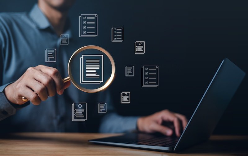 business, document, management, corporate, file, information, laptop, folder, professional, organization. close up to businessman, one hand typing keyboard, another hold magnifier to search document.
