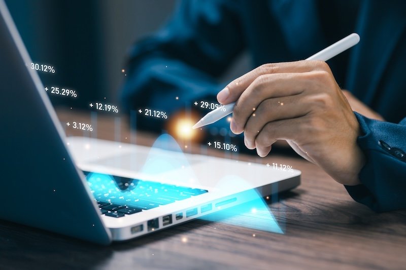 Hand using stylus to analyze floating percentage data chart on laptop, highlighting digital analytics, business metrics, performance evaluation, and financial insights in modern technology environment.