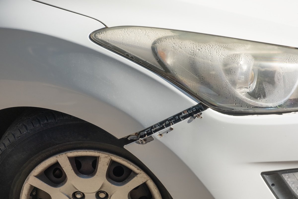 Car bumper was roughly reattached using visible screws. broken headlights, scratches, dents, and faded paint on body parts