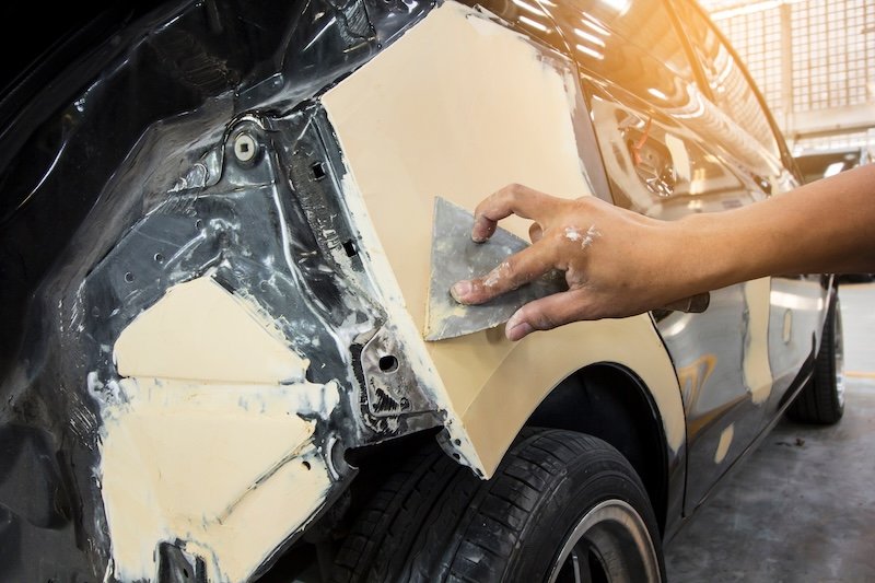 Repairing car damage body by puttying work  by sanding primer before Spraying color. Claim the insurance company. image blur focus style.