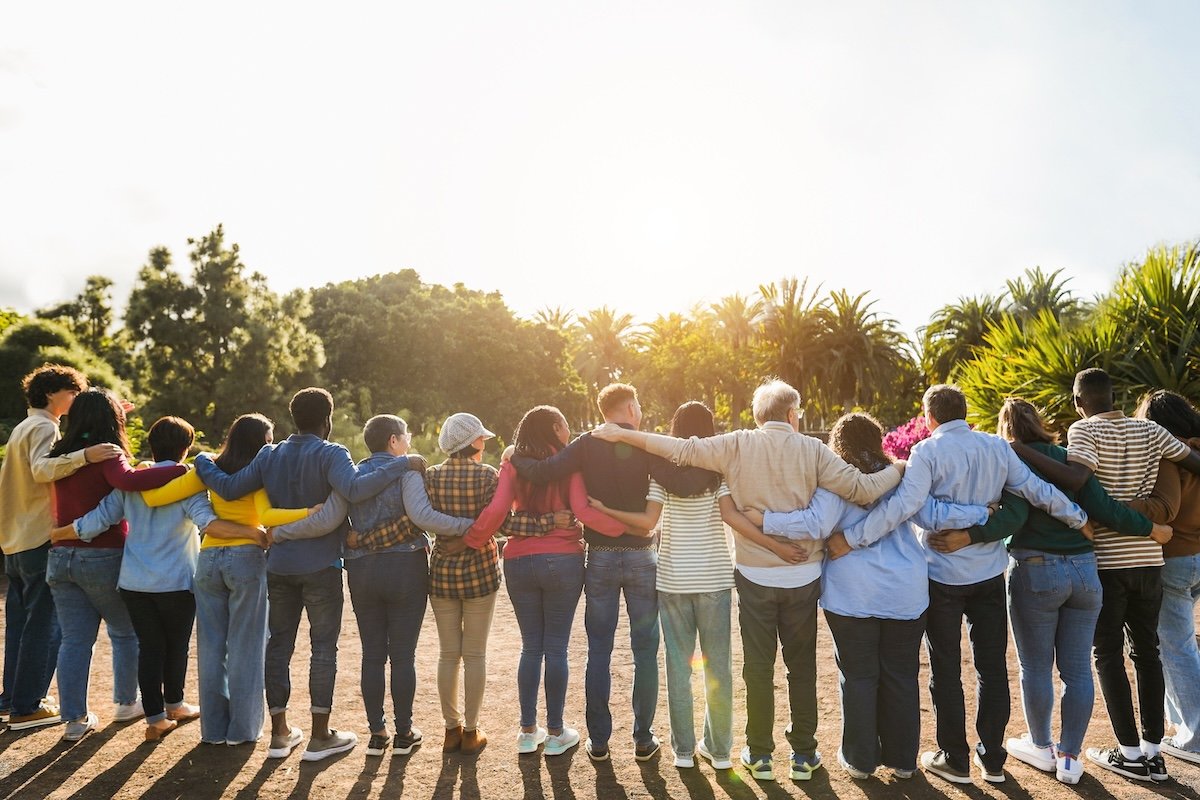 Group of multigenerational people hugging each others - Support, multiracial and diversity concept - Main focus on senior man with white hairs