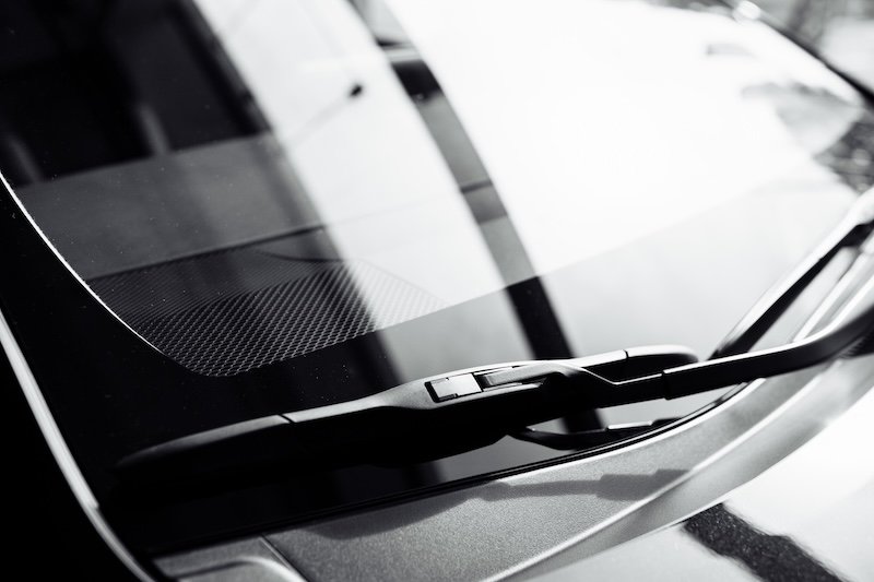 close up of front Windshield Wipers on a black new car in salon wind noise